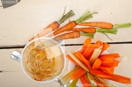 Image of fresh hummus dip with raw carrot and celery 