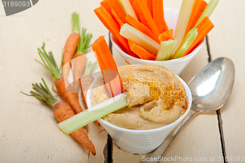 Image of fresh hummus dip with raw carrot and celery 