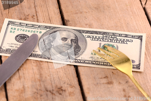 Image of american money on wooden plate with knife and fok