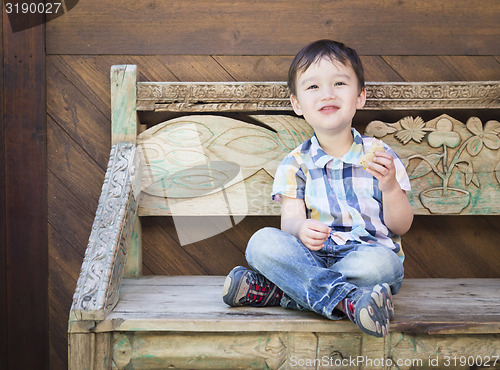 Image of Cute Mixed Race Boy Sitting on Bench Eating Sandwich