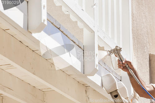 Image of House Painter Spray Painting A Deck of A Home