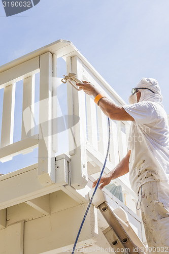 Image of House Painter Spray Painting A Deck of A Home