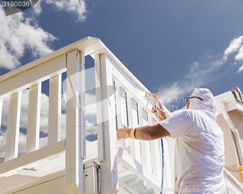 Image of House Painter Spray Painting A Deck of A Home