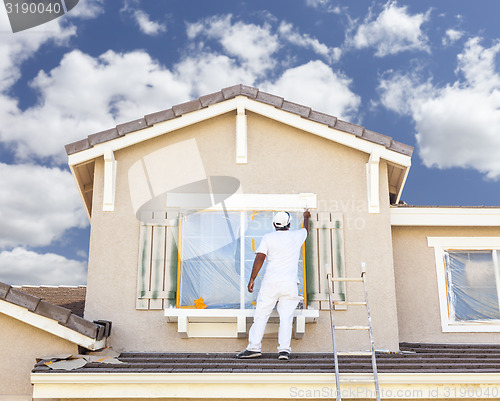 Image of House Painter Painting the Trim And Shutters of Home