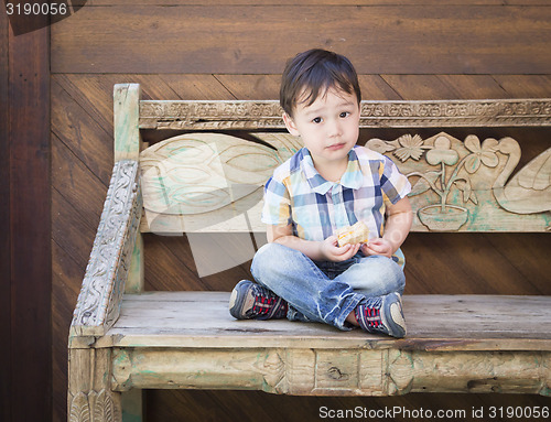 Image of Cute Mixed Race Boy Sitting on Bench Eating Sandwich
