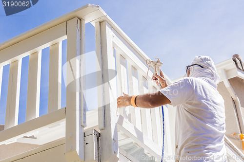 Image of House Painter Spray Painting A Deck of A Home