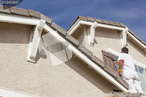 Image of House Painter Painting the Trim And Shutters of Home