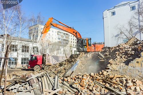 Image of Excavator loads garbage from demolished house