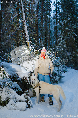 Image of Woman with dog in winter forest on a walk
