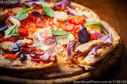 Image of Homemade pizza with dried tomatoes and salami 