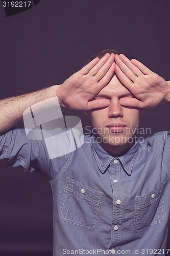 Image of man covering face with his both hands