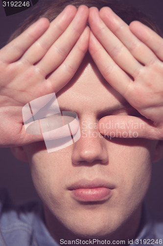 Image of man covering face with his both hands