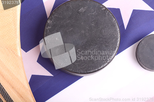 Image of Hockey equipment including a stick and puck on an American flag to infer a patriotic American sport.