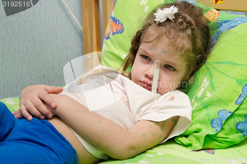 Image of Little girl lying in bed with a thermometer