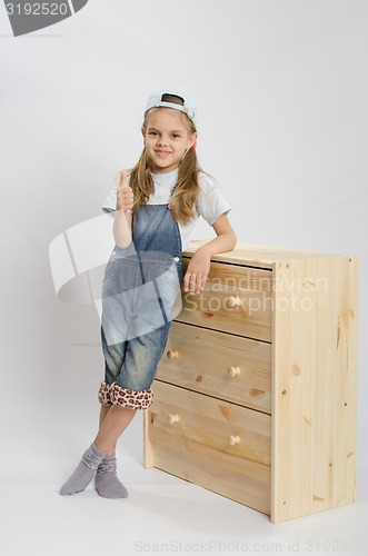 Image of Girl in overalls collector of furniture based on the chest shows class