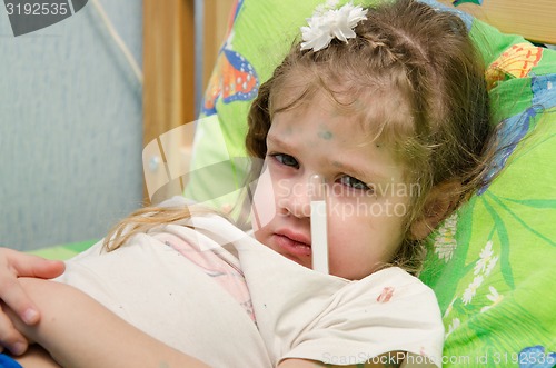 Image of Little girl lying in bed with a thermometer