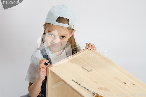 Image of Little girl in image collector of furniture turn screw