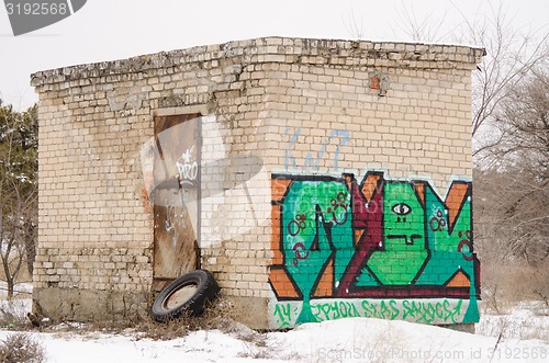 Image of old one-story brick building a rusty door with graffiti on wall