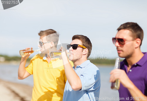 Image of happy friends with beer bottles on beach