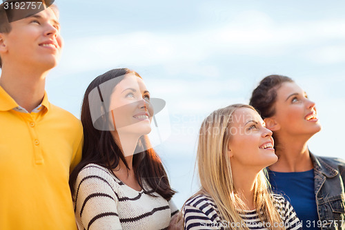 Image of group of happy friends looking up on beach