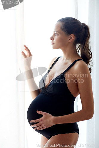 Image of happy pregnant woman with big bare tummy at home