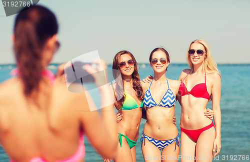 Image of group of smiling women photographing on beach