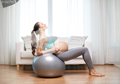 Image of happy pregnant woman exercising on fitball at home