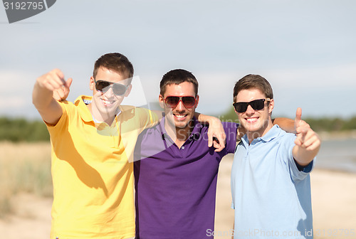 Image of smiling friends in sunglasses showing thumbs up