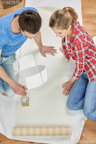 Image of close up of couple smearing wallpaper with glue