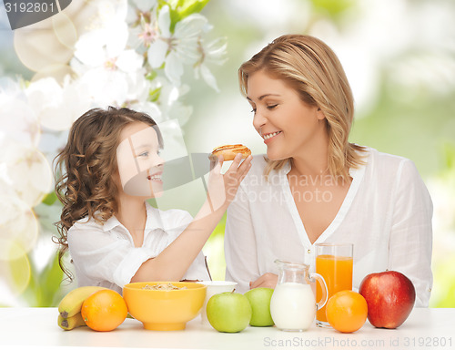 Image of happy mother and daughter eating breakfast