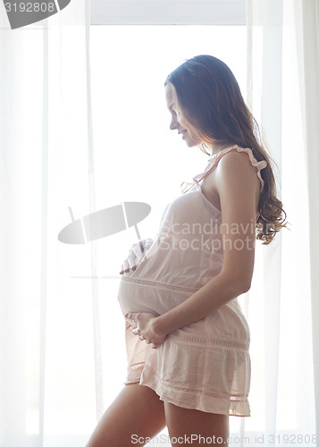 Image of happy pregnant woman with big bare tummy at home