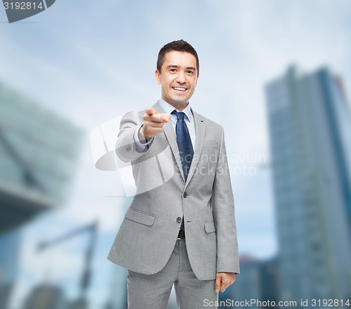 Image of happy smiling businessman in suit pointing at you