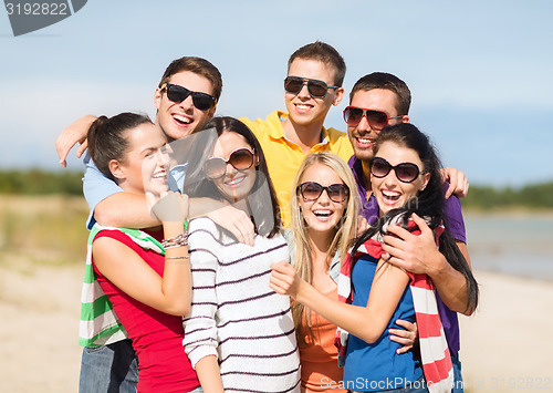 Image of group of happy friends hugging on beach