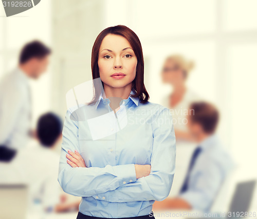 Image of smiling businesswoman with crossed arms at office