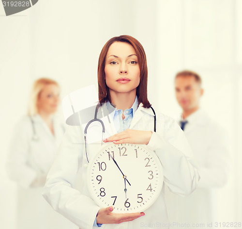 Image of calm female doctor with wall clock