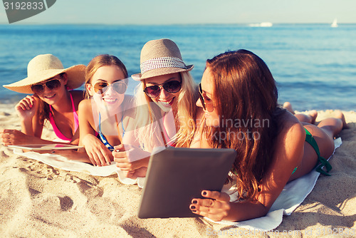 Image of group of smiling young women with tablets on beach