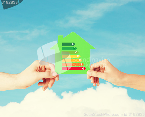 Image of hands holding green paper house