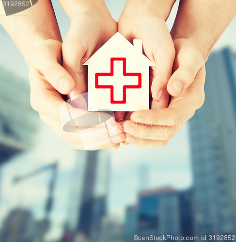 Image of hands holding paper house with red cross