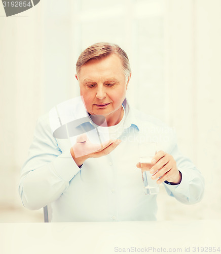 Image of old man with pills ang glass of water