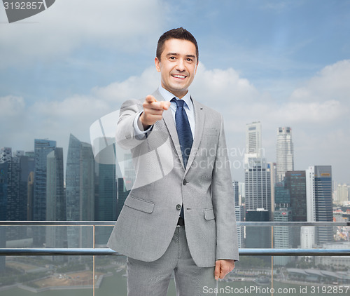 Image of happy smiling businessman in suit pointing at you