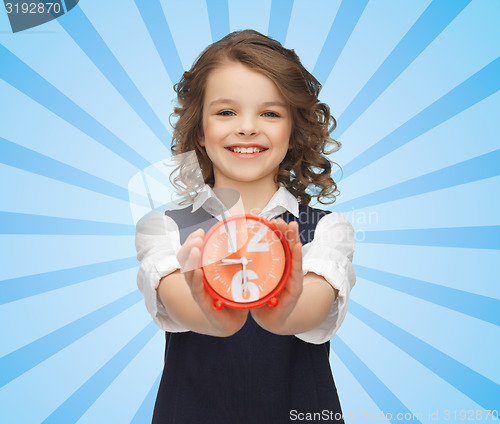 Image of happy girl with alarm clock over blue 