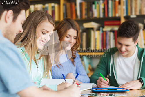 Image of happy students writing to notebooks in library