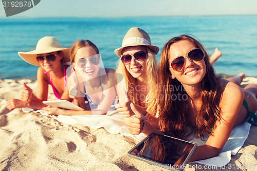 Image of group of smiling young women with tablets on beach