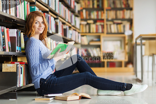 Image of happy student girl reading book in library