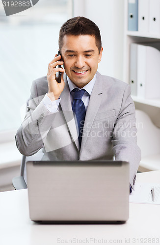 Image of smiling businessman with laptop and smartphone