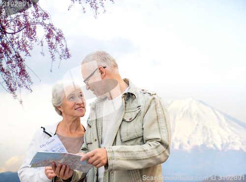 Image of happy senior couple with travel map over mountains