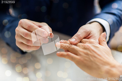 Image of close up of male gay couple hands and wedding ring