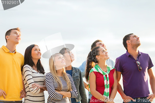 Image of group of happy friends looking up on beach