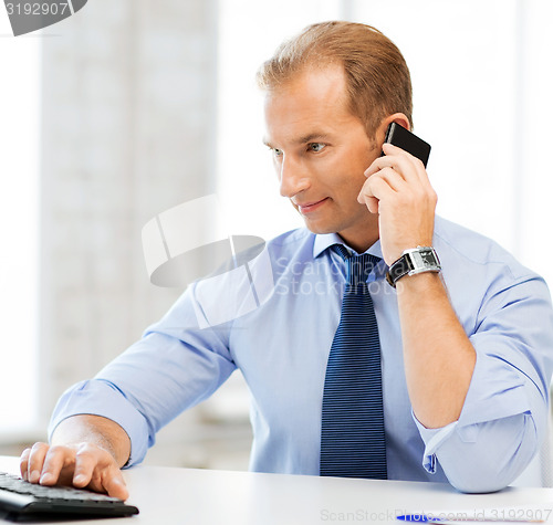 Image of smiling businessman with smartphone in office