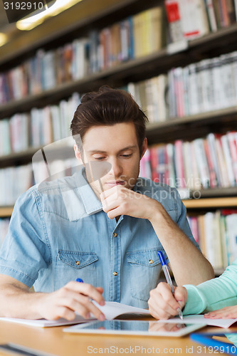 Image of male student with tablet pc networking in library